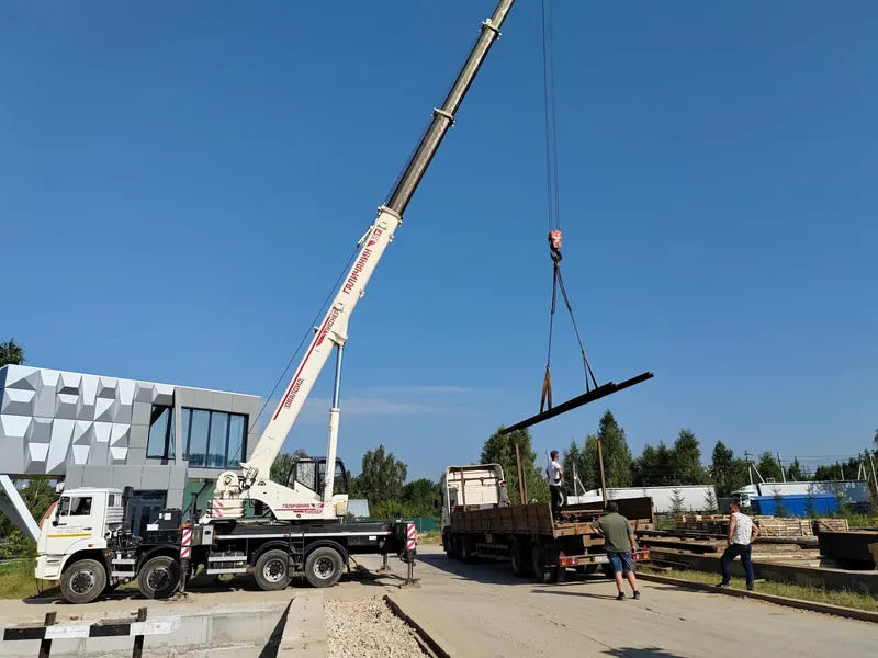 Крановая погрузка длинномерной металлической балки на открытой площадке