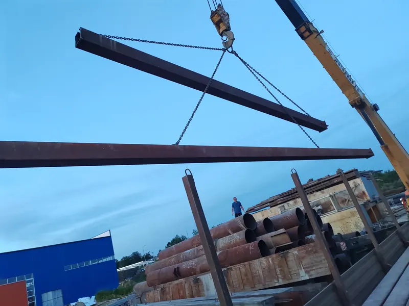 Крановая погрузка длинной стальной балки на бортовой полуприцеп
