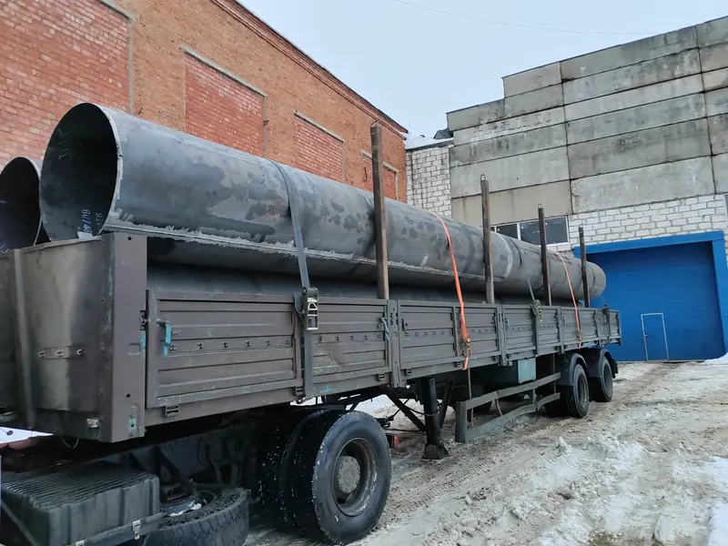 Трубы большого диаметра на бортовом полуприцепе у промышленного здания