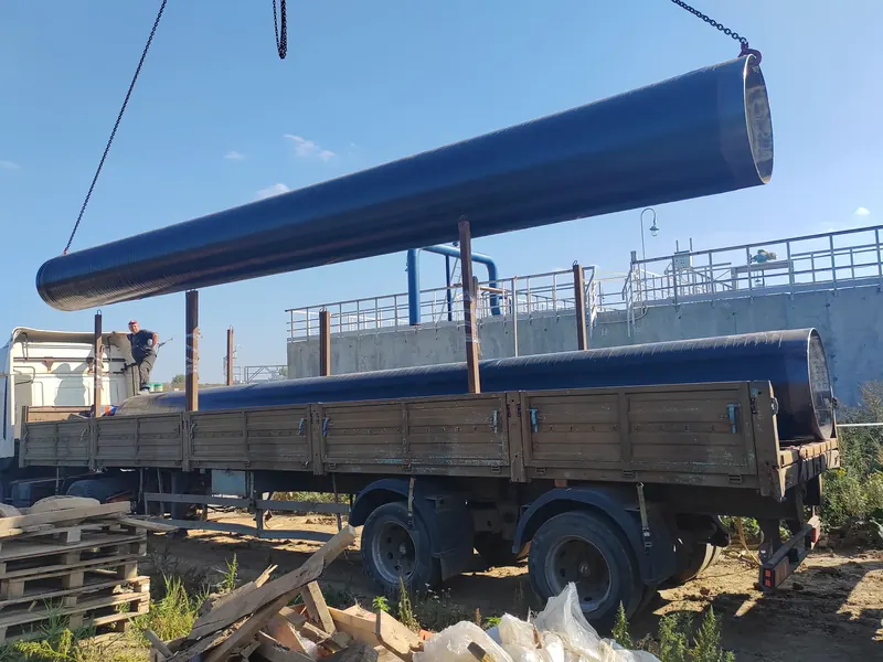 Труба большого диаметра на стропах над бортовым полуприцепом